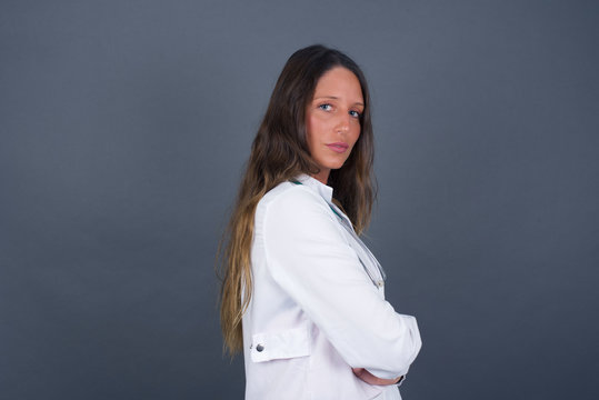 Profile Of Doctor Woman With Healthy Pure Skin Has Braided Hairstyle Wears Black Clothes Has Contemplative Expression Ready To Have Outdoor Walk Isolated Over Grey Studio Wall With Copy Space.