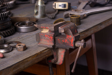 Old rusty vise and various hand tools on a wooden table.
