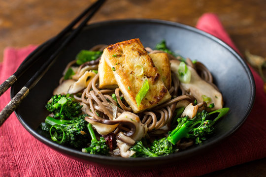 Close up view of stir fried noodles with shiitakes and baby broccoli