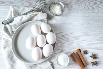 Baking ingredients. Eggs in a plate with napkin on white wooden background. Easter composition, mockup.  Bakery background frame.