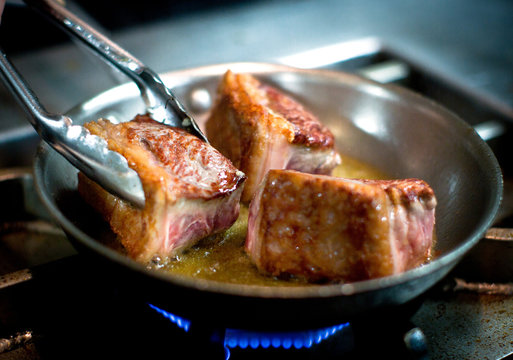 Selective focus of searing beef cheeks on stove