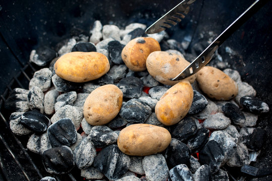 Close up view of ash cooked potatoes in barbecue
