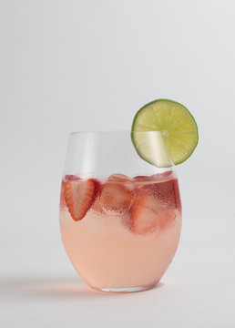 Pink cocktail in glass with lime splice