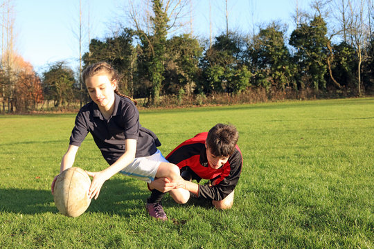 Teenage boy and girl playing rugby