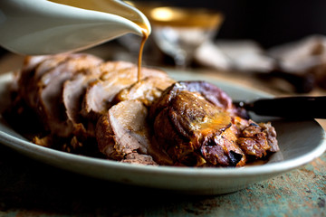 Selective focus of gravy pouring on roasted pork