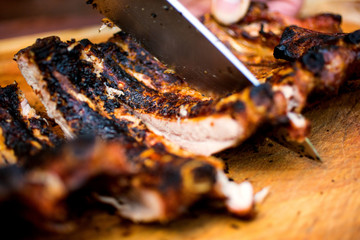 Grilled baby back ribs cutting with knife on wooden board