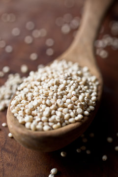 Selective focus of spoon full sorghum grains on wooden board