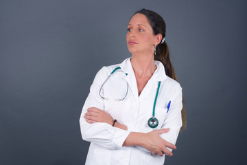 Image of upset pretty young caucasian lady standing indoors with arms crossed. Looking with disappointed expression aside after listening to bad news. Confident girl.