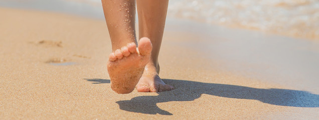 child walks along the beach leaving footprints in the sand. Selective focus.