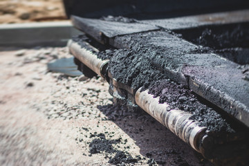 Asphalt paver machine and steam road roller during road construction and repairing works, process of asphalting and paving, workers working on the new road construction site, placing a layer
