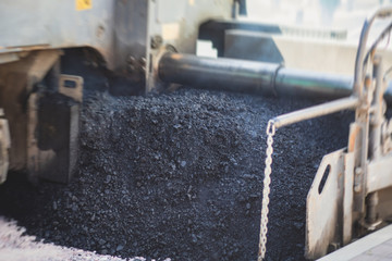 Asphalt paver machine and steam road roller during road construction and repairing works, process of asphalting and paving, workers working on the new road construction site, placing a layer