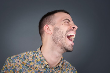 Joyful European man having fun and laughs at good joke or sings wears casual clothes, standing...