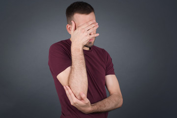 Indoor portrait of handsome man with stylish haircut, wearing casual clothes, making facepalm...