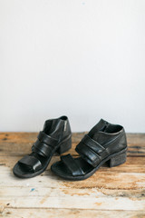 Black leather heeled sandals on wooden table