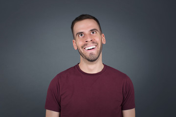 People and sudden reaction concept. Surprised caucasian handsome male student, shrugs shoulders, looking sideways, being happy and excited about new plans with friends. Isolated over gray wall.