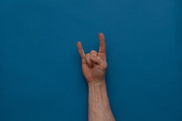 Rock gesture on a blue background.