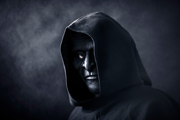 Fototapeta na wymiar Scary figure in hooded cloak with mask