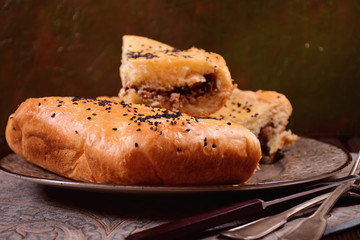 Brown dish with meat, raisins and nuts on a brown dish and silver forks