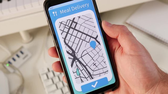 Meal delivery app on a smartphone showing on a live map the delivery car approaching its destination.