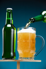 Two beer bottles and a glass on a wooden stand