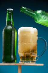 Two beer bottles and a glass on a wooden stand