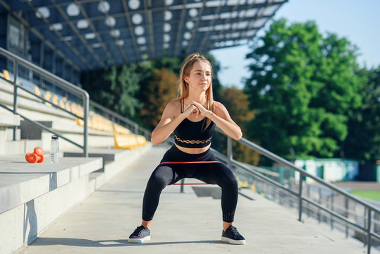 Young sporty woman doing exercises with rubber band outdoor
