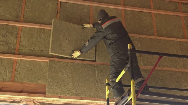 Man puts a sheet of insulation on the scaffolding