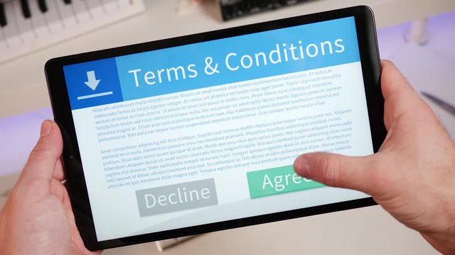Reading and pressing the AGREE button at the end of the terms and conditions agreement on a tablet screen. Digital contract being accepted.