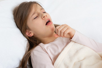 Fototapeta na wymiar Little cute girl lies in bed and coughs violently with a cold, virus, gets sick