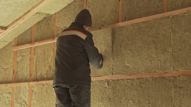 Man puts a sheet of insulation in the gable frame house