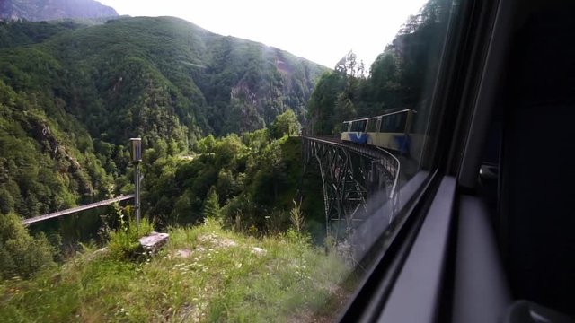 Scenic train Centovalli Railway Locarno-Domodossola on bridge.  Intragna village. Swiss Alps, Ticino Switzerland tourism in summer. Slow motion.