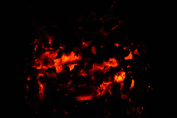 Fototapeta na wymiar Background of burning hot coals. The flickering of burning coals in the night. Closeup