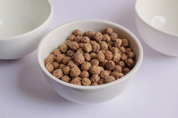 Chocolate cereal pops in white cup on white table