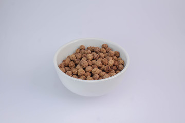 Chocolate cereal pops in white cup on white table