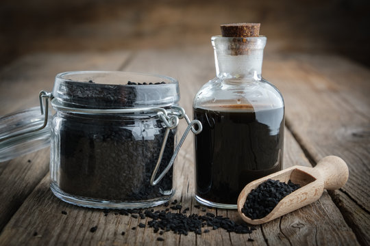 Jar of black cumin or roman coriander seeds and black caraway oil bottle. Ingredients for cooking. Ayurveda treatments.