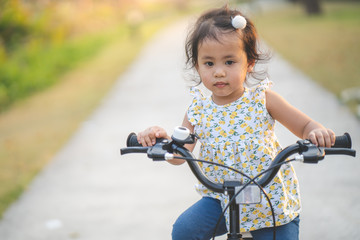 Fototapeta na wymiar Lovely little asian girl riding a bike at bike lane outdoor.