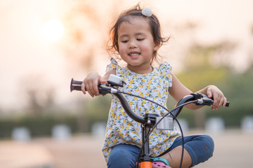 Fototapeta na wymiar Happy little girl ride a bicycle in the park