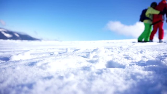 A skiers silhouettes with a ski poles slowly moving uphill on an anchor ski lift leaving traces in the snow on a clear blue sky background. Ski resort in the snowy mountain woods.
