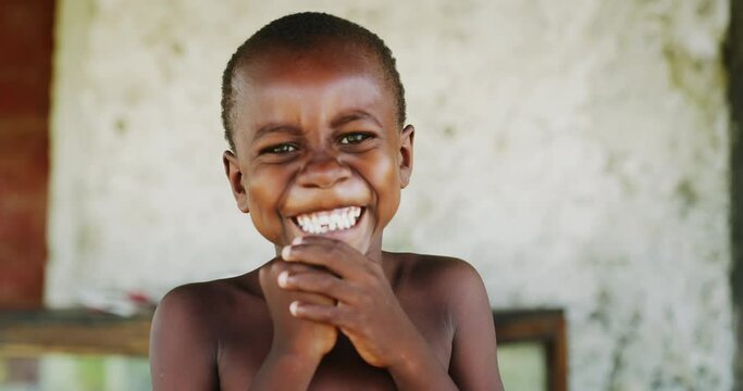 Authentic portrait of happy rural african  boy is smiling in camera on a village background. Concept: charity, people,life, happiness, authenticity