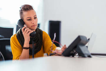 Businesswoman using landline phone in the office