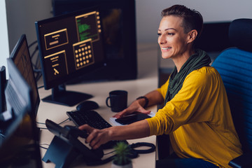 Happy businesswoman sitting by the desk and working