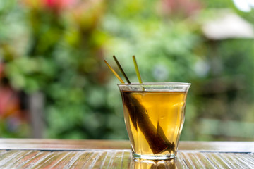Healthy, refreshing drink of cinnamon and stalks of ginger on a wooden table in a tropical garden