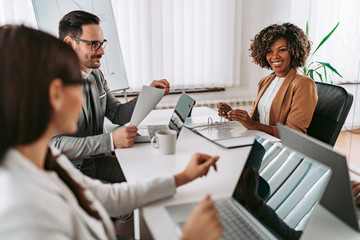 Portrait of cheerful businesswoman discussing with colleagues at the meeting and smiling