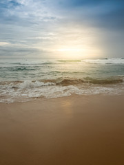 Beautiful image of sun rising over the calm ocean surface and sandy beach