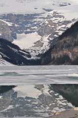 Snow on mountain by lake with trees on sides