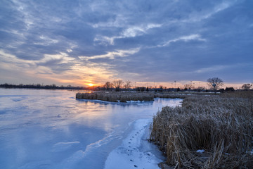 Scenic View of Winter Lake Sunset with Blue Sky and Iced Over Lake with Cattails 