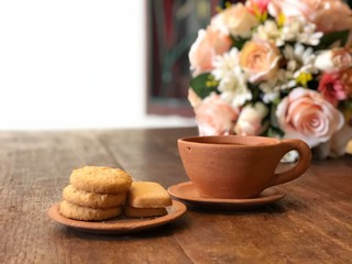 Brown clay teacup and cookies on wooden table