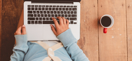 Beatiful girl used Laptop and coffee cup in girl's hands sitting on a wooden floor at home