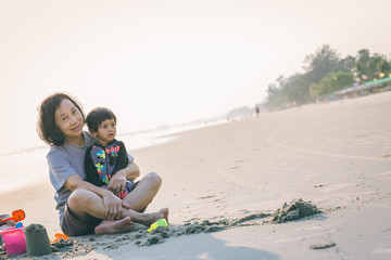 Family playing on the beach. Parents and children relaxing on the beach in the summer.happy healthy family Grandmother and Nephew building sand castle on the beach smiling and carefree.