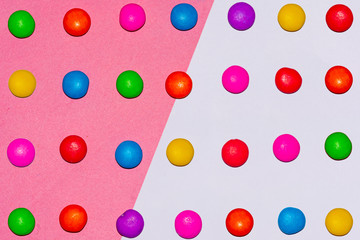 Chocolate coated candies on pink and white background